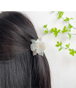 Close-up of a white pearlescent 3D rose flower hair claw clip on dark hair