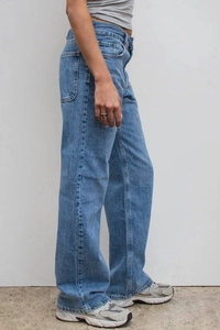 Detail view of mid-blue washed straight leg jeans with side seam stitching and pocket detail