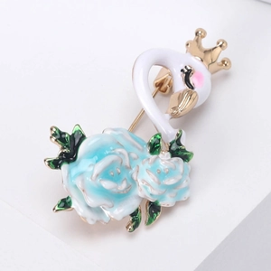 Elegant white swan brooch with gold crown and blue rose detail on white pedestal