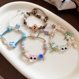 Detail of four handmade ceramic cat charm bracelets with colorful woven ropes and beads