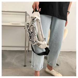 Détail du sac bandoulière transparent en PVC avec bordure blanche et breloque damier