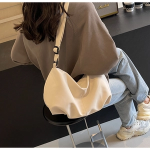 Detailed view of cream nylon tote bag featuring adjustable shoulder strap and matte finish