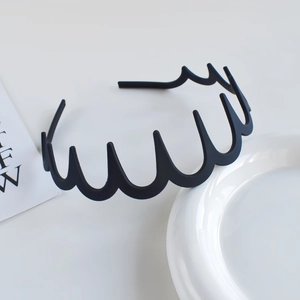 Detail of a matte black wavy headband with teeth for secure hold and minimalist style