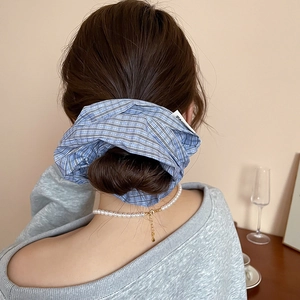 Detail showing blue plaid scrunchie and pearl necklace on a model with elegant styling