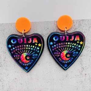 Makroaufnahme von Ouija-Herz-Ohrringen aus Acryl mit orangen Steckern auf grauem Stein