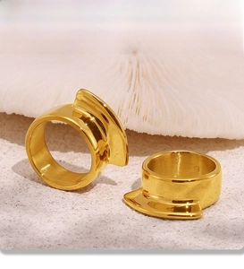 Detailed macro shot of 18k gold plated stainless steel geometric rings on beach sand