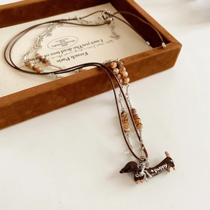 Detail view of double-layer dachshund pendant necklace with brown leather cord and beads