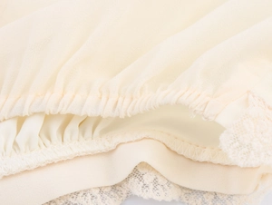Détails du tissu en mousseline crème avec smocks élastiques et bordure en dentelle