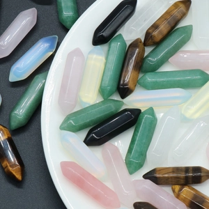 Various hexagonal natural crystal pillars in pink green and black displayed on a white tray