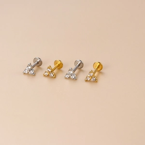 Detailed view of gold and silver flat back stud earrings with three-stone zircon triangles