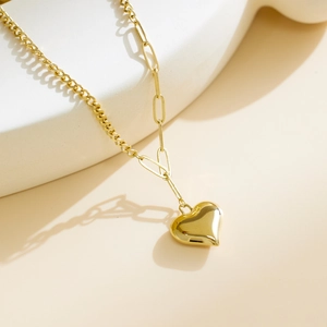 Detalle de collar de cadena cubana dorada y clip con un colgante de corazón