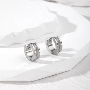 Macro view of silver stainless steel hoop earrings with engraved herringbone texture