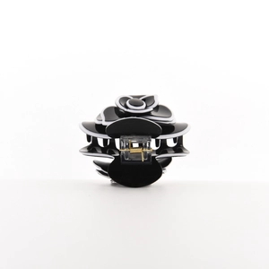 Detailed close-up of a black and white camellia hair claw clip with golden metal spring