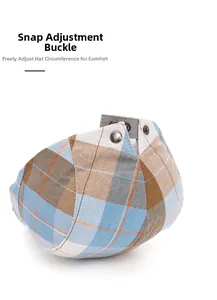 Detail of plaid beret hat featuring adjustable metal buckle and herringbone fabric texture