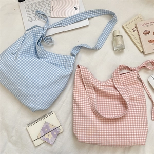 Close-up of pink and blue gingham canvas tote bags with knot detail on white fabric