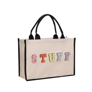 Beige canvas tote bag with black trim and colorful chenille STUFF letter patches