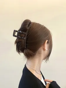 Close-up of large geometric hollow hair claw clip securing a sophisticated updo hairstyle
