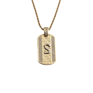Détail d'un pendentif doré à texture tressée avec lettre S argentée et zircons