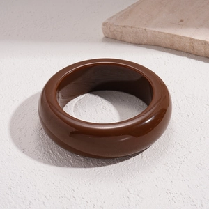 Polished dark brown acrylic geometric bangle on natural stone background setting