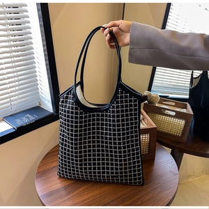 Detail of black tote bag with silver rhinestone grid pattern on a wooden table