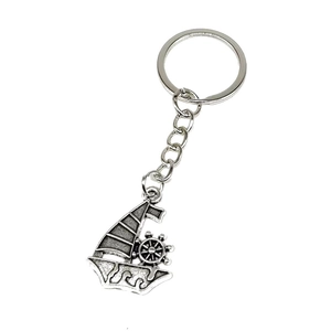 Macro detail of retro silver nautical keychain with sailing boat and ship wheel pendants
