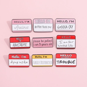 Macro view of assorted enamel pins with witty English quotes on a pastel pink background