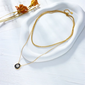 Detail of gold double-layer necklace with blue evil eye pendant on ceramic tray