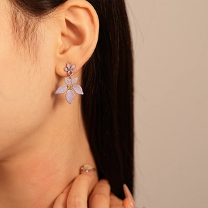 Gros plan d'un mannequin portant des boucles d'oreilles fleurs violettes mates