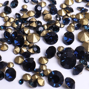Close-up of sparkling dark blue and gold pointed back rhinestones for nail art design