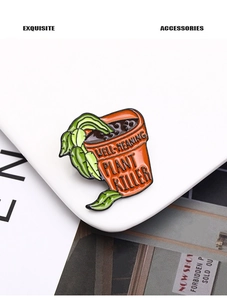 Détail macro d'une broche en émail avec texte Well-Meaning Plant Killer sur pot orange