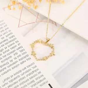 Detail of gold heart pendant with five-point stars and zircons on a white floral background