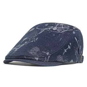 Detailed close-up of dark blue denim newsboy cap with white splatter pattern and metal buckle