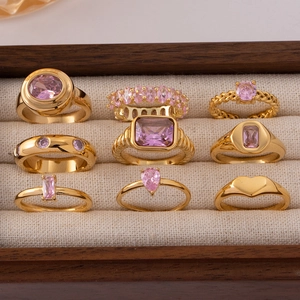 Set aus Goldringen mit rosa Zirkonia in einer Holz-Schmuckschatulle auf beigem Stoff