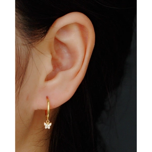 Close-up of a gold s925 silver hoop earring with a sparkling diamond butterfly charm