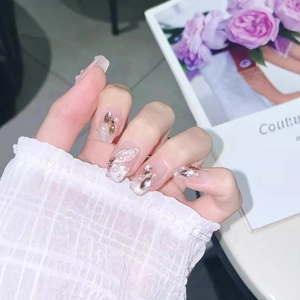 Nude translucent press-on nails with butterfly motifs, pearls and glitter accents