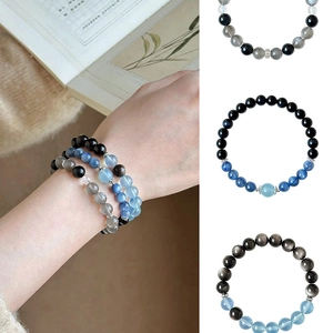 Detail of moonstone and obsidian beaded bracelets on wrist and white background