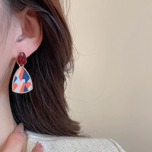 Close-up of geometric resin earrings in red and blue, worn by a model in profile