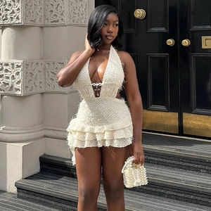 Dettaglio di un miniabito bianco all'americana con trama in pizzo e bordo con frange