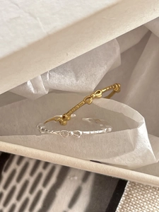 Close-up of gold and silver bow-shaped rings on white pleated paper in a gift box