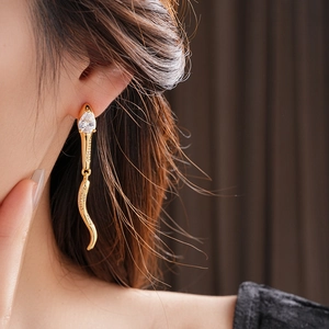 Detail of snake-style drop earring with pear-shaped zircon on a fashion model