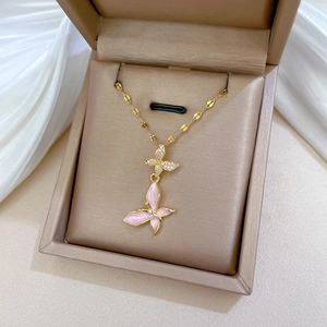 Close-up of gold titanium necklace featuring a pink enamel butterfly and crystal pendant