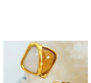 Macro view of geometric gold earrings with textured milk white and amber stone inlay