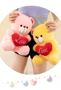Detail view of model holding pink and yellow plush teddy bears with red Love hearts