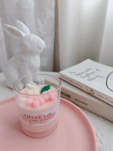 Detail of pink strawberry cup candle with floral wax decorations in a lifestyle setting