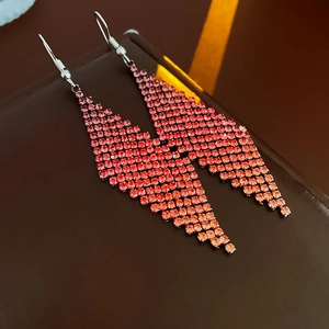 Gros plan de boucles d'oreilles géométriques à franges avec strass dégradés rose-orange