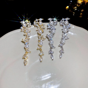 Detail view of gold and silver tassel earrings with pearls and marquise cubic zirconia