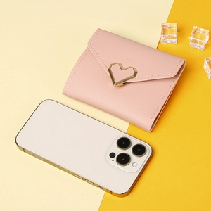 Pink short tri-fold wallet with gold heart buckle next to a phone for size comparison