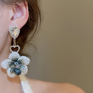 Dettaglio ravvicinato di orecchini a fiore con cristalli blu indossati su modella
