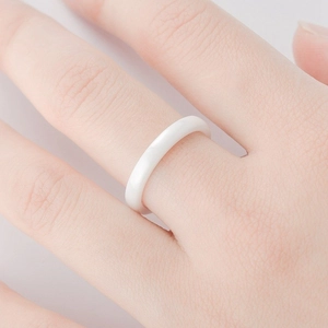 Macro view of a 3mm minimalist white ceramic ring with a smooth rounded surface on hand