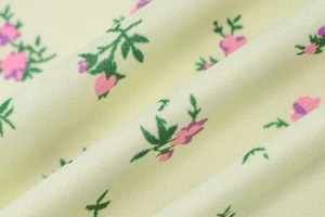 Detailed macro view of soft light yellow fabric with purple floral print and green leaves